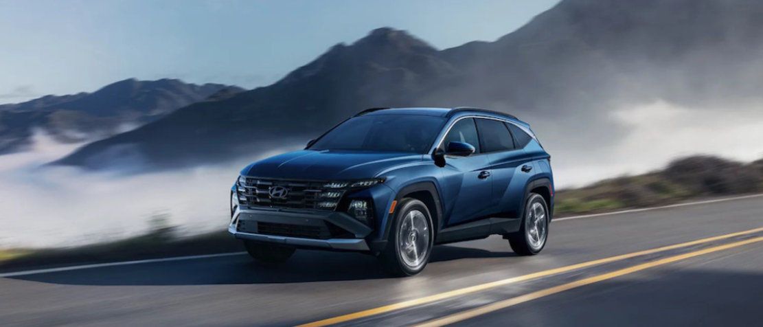 A blue 2025 Hyundai Tucson driving down a misty mountain road