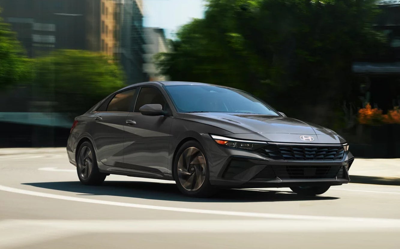 A dark gray 2026 Hyundai Elantra Hybrid sedan turning a corner on a city street